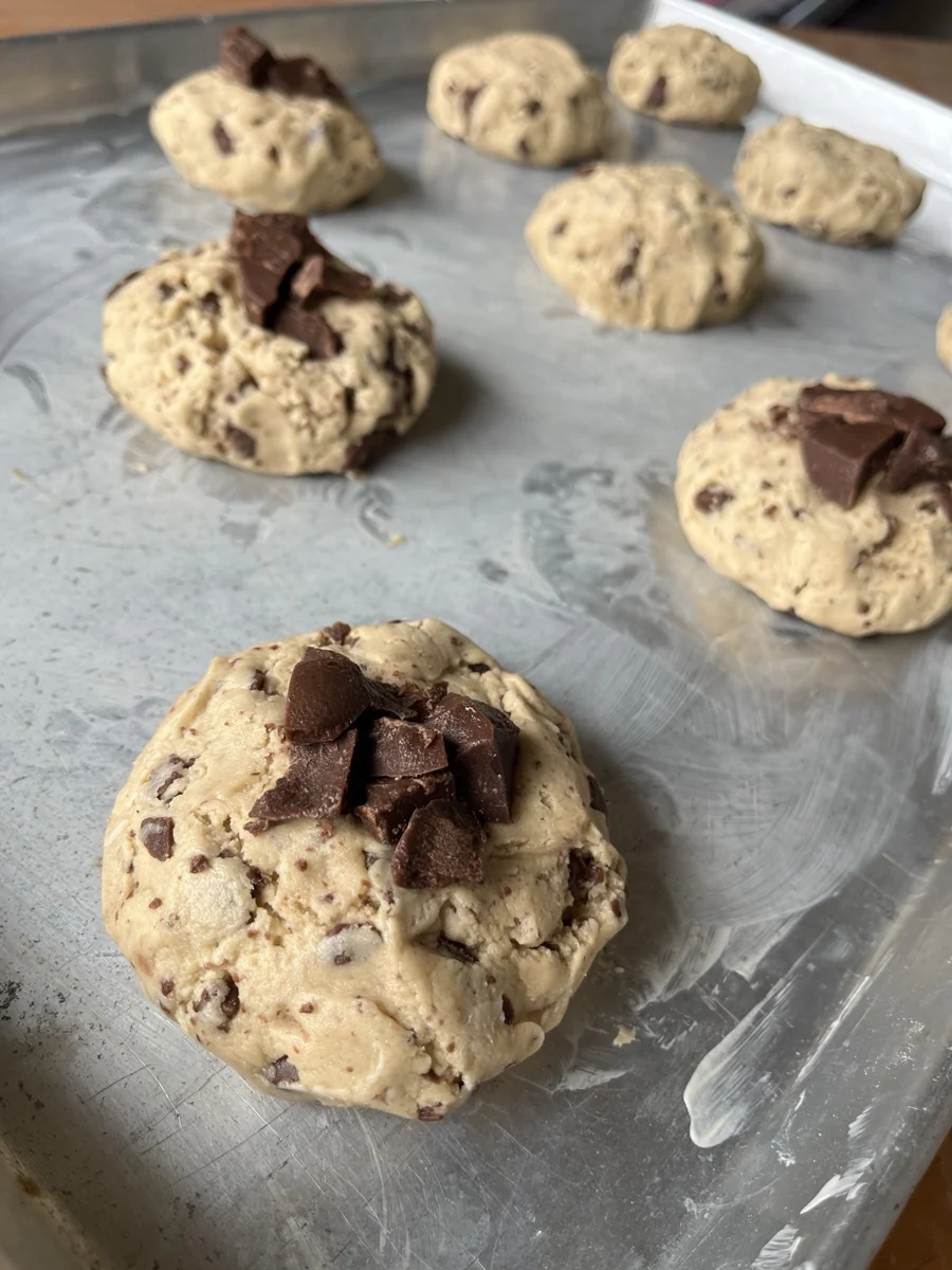 Porções de massa de cookie com pedaços de chocolate, modeladas antes de assar